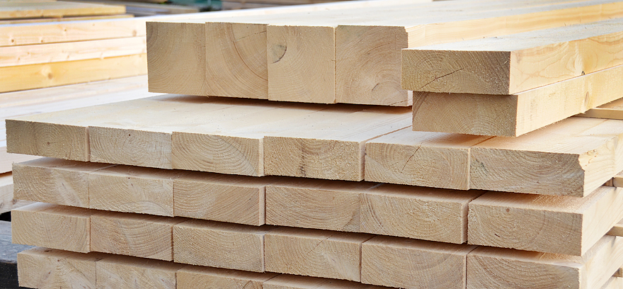 Große Stapel aus Bauholz und Holzbrettern im Außenlager Gestapelte Holzlatten und Bretter auf dem Holzlagerplatz Bauholz und Schalungsbretter ordentlich gelagert im Freien Holzbretter und Lattenpakete für den Holzbau im Lager Gelagerte Holzbretter und Bauholz vor einer Lagerhalle