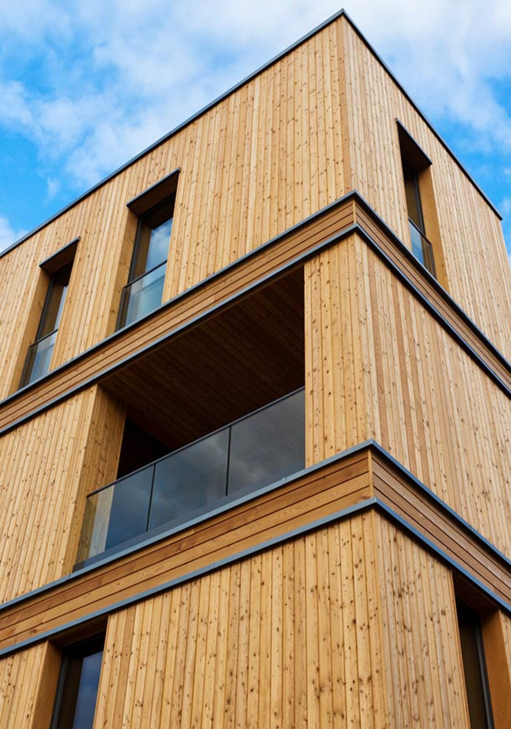 Mehrstöckiges Wohngebäude mit natürlicher Holzfassade und modernen Balkonen