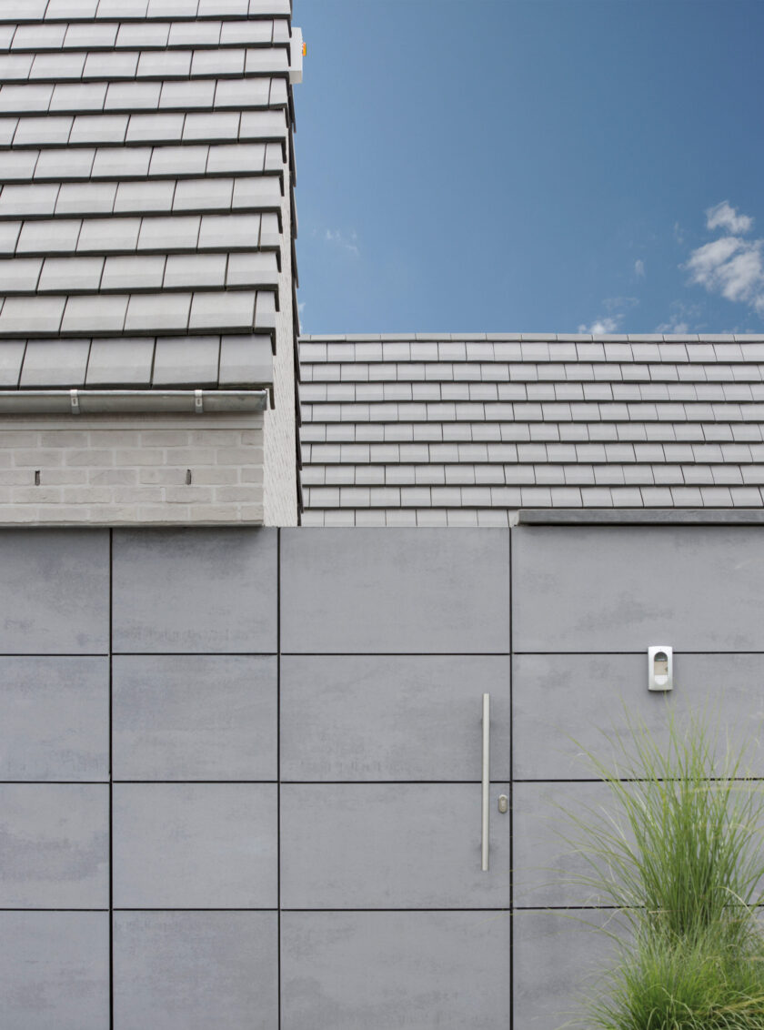 Moderne Hausfassade mit grauen Faserzementplatten und klaren geometrischen Linien