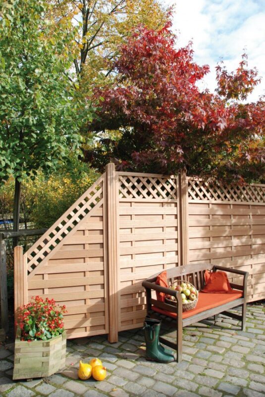 Moderner Sichtschutzzaun aus horizontalen Holzlatten auf einer Terrasse mit Pflanzkübeln