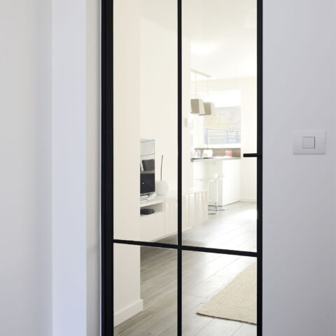 Moderne schwarze Glastür mit Stahlrahmen zwischen Flur und Wohnraum