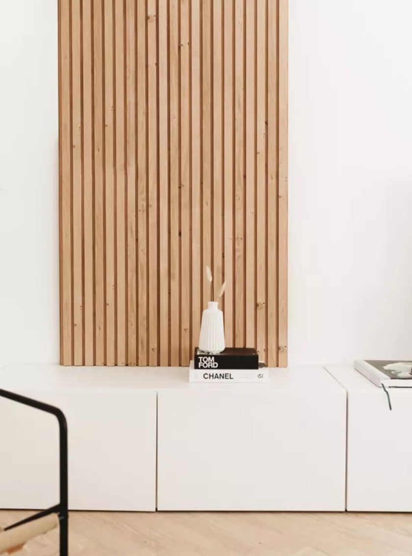 Moderne dunkle Holz-Akustikpaneele hinter hellem Sessel mit Designleuchte