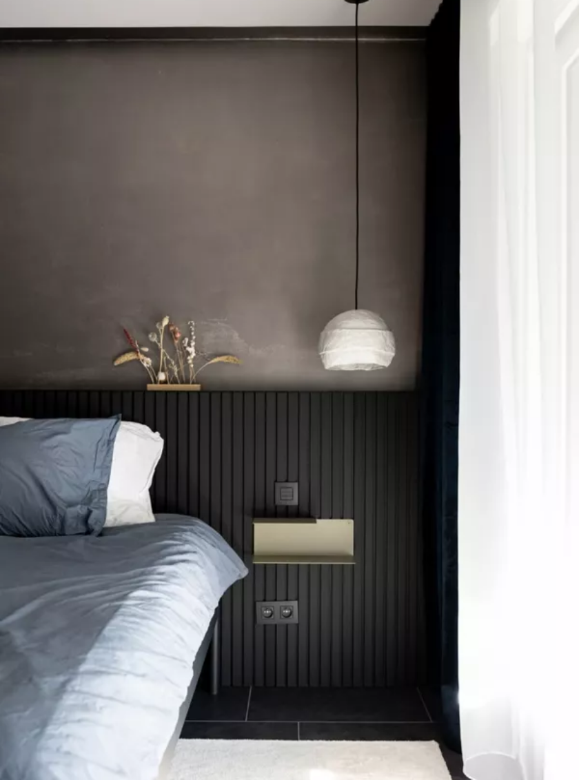 Moderne dunkle Holz-Akustikpaneele hinter hellem Sessel mit Designleuchte