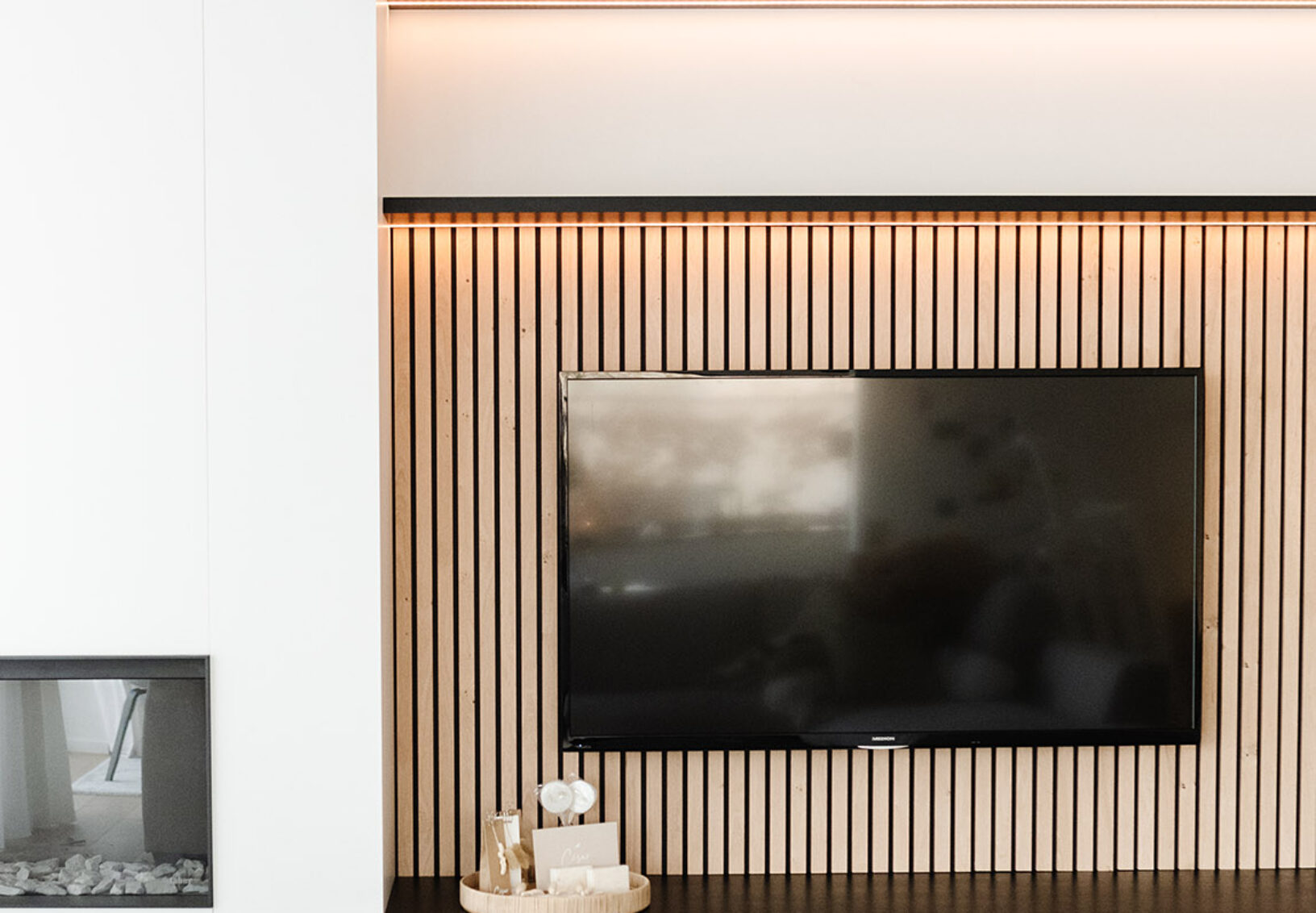 Moderne TV-Wand mit vertikalen hellen Holz-Akustikpaneelen und indirekter Beleuchtung