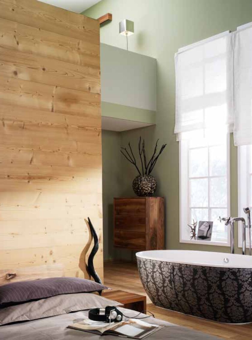 Gemütliches Schlafzimmer mit rustikaler Holzpaneelwand und freistehender Badewanne